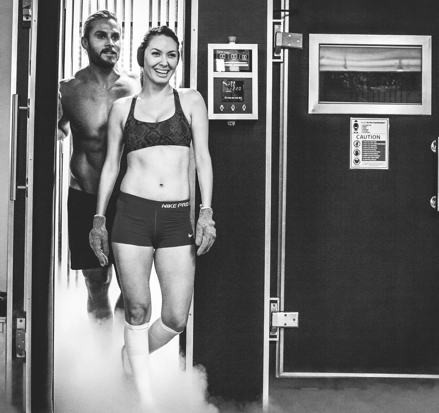 Two clients stepping out of the cryochamber as fog spills across the floor