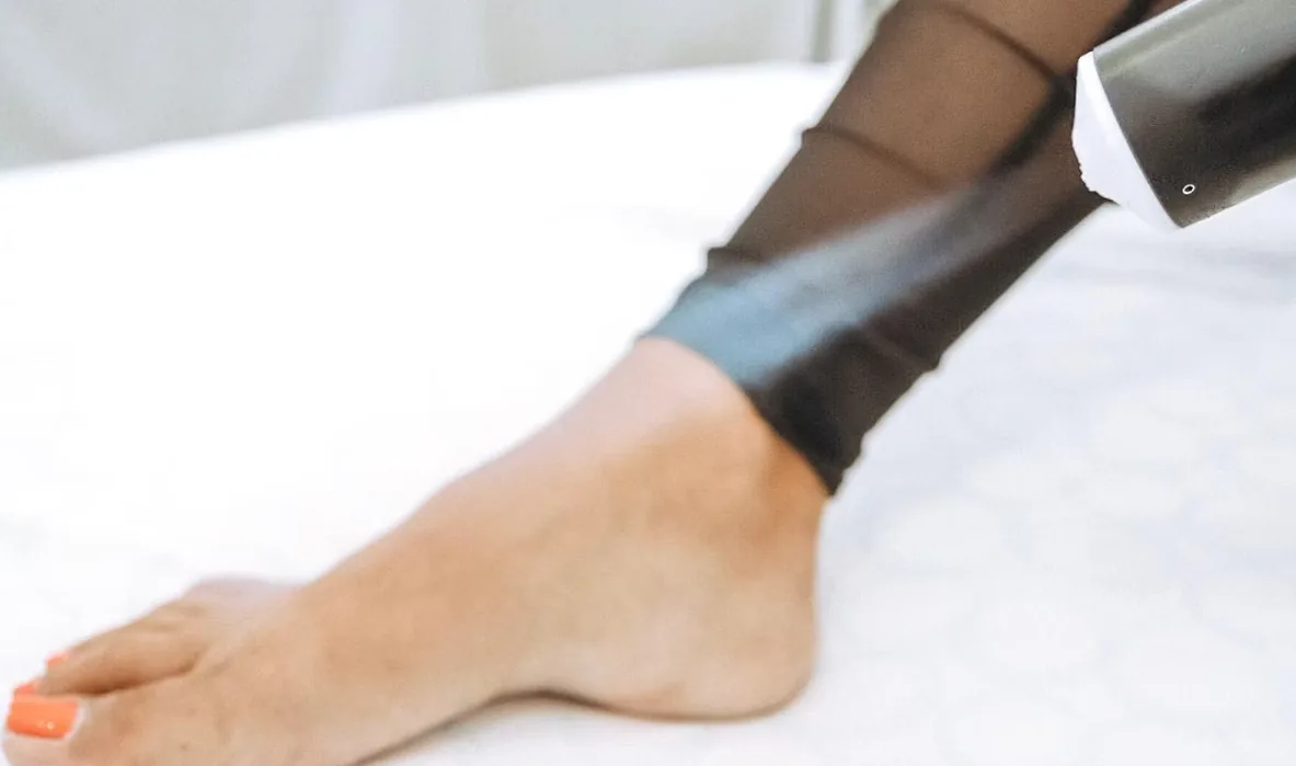 Local cryotherapy being applied to a client's ankle with a handheld wand