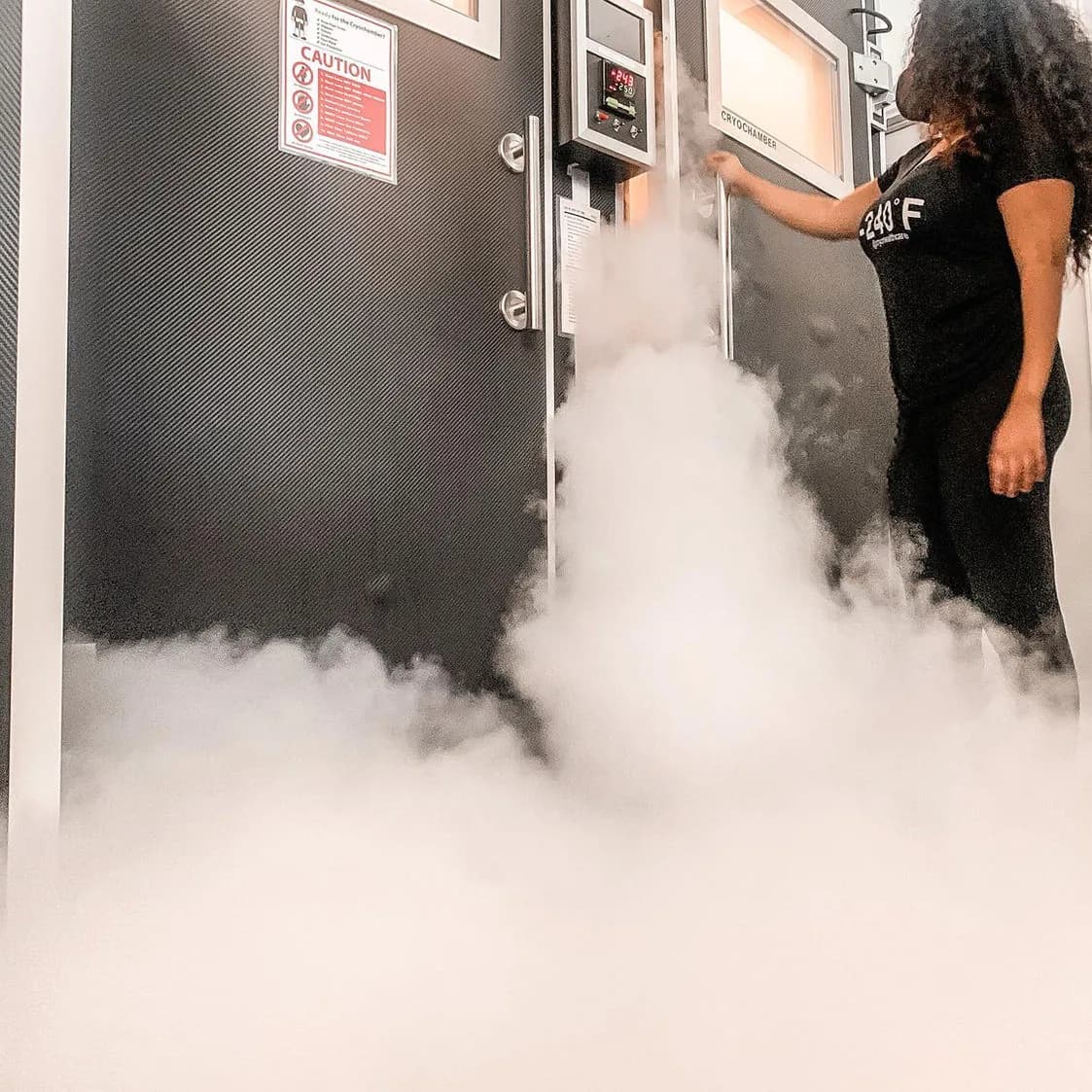 A Cryohealthcare operator running a whole body cryotherapy session as fog rolls from the chamber